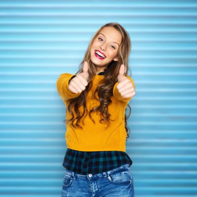 happy young woman or teen girl showing thumbs up